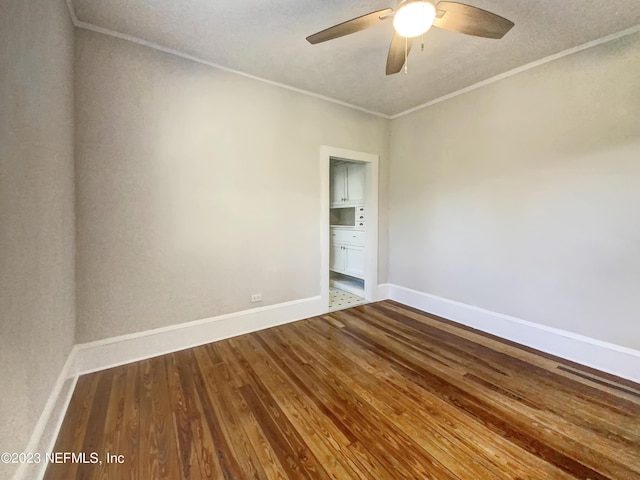 empty room featuring hardwood / wood-style floors, ceiling fan, and ornamental molding