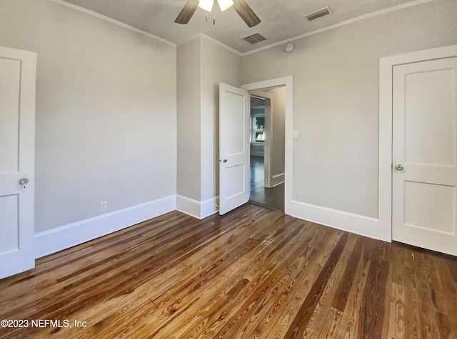 unfurnished bedroom with ceiling fan, ornamental molding, and dark wood-type flooring