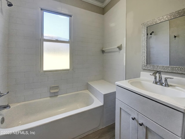 bathroom featuring wood-type flooring, vanity, ornamental molding, and tiled shower / bath