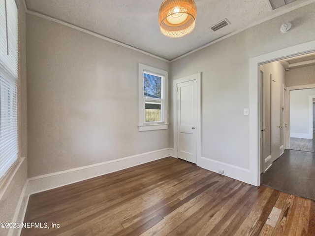 unfurnished room with crown molding, dark hardwood / wood-style flooring, and a textured ceiling