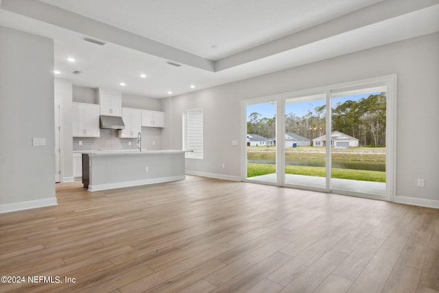 unfurnished living room featuring sink and light wood-type flooring