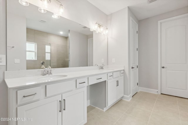 bathroom with tile patterned flooring, a tile shower, and vanity