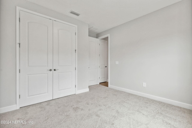 unfurnished bedroom featuring a closet and light colored carpet