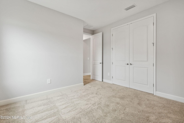 unfurnished bedroom featuring light carpet and a closet