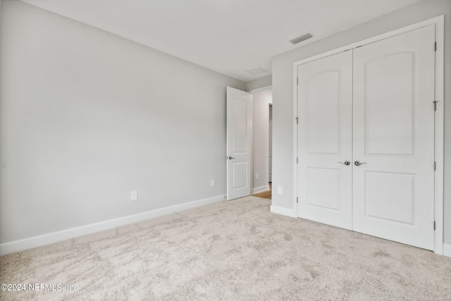 unfurnished bedroom with light carpet and a closet