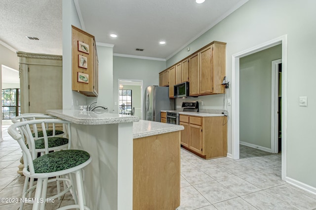 kitchen featuring stainless steel appliances, crown molding, light countertops, a kitchen bar, and light tile patterned flooring