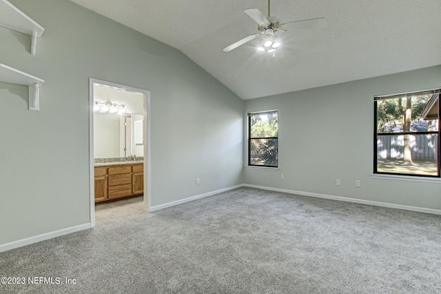 unfurnished bedroom featuring light carpet, baseboards, a ceiling fan, lofted ceiling, and ensuite bathroom