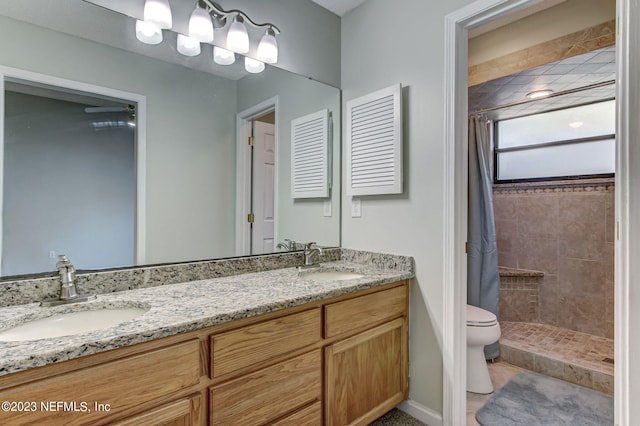 full bath with a tile shower, a sink, and toilet