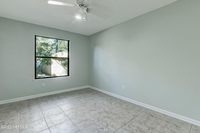 empty room with ceiling fan, a textured ceiling, light tile patterned flooring, and baseboards