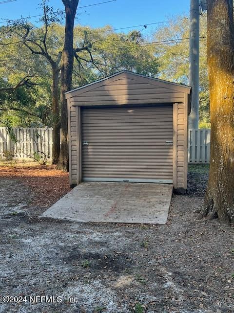 detached garage featuring driveway and fence