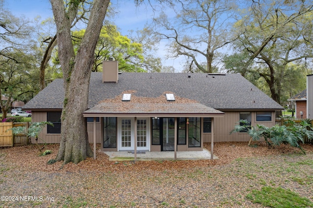 back of house with french doors, a chimney, a shingled roof, and fence