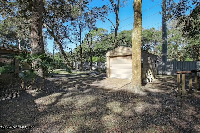 view of yard featuring a storage shed, a fenced backyard, a detached garage, and an outbuilding