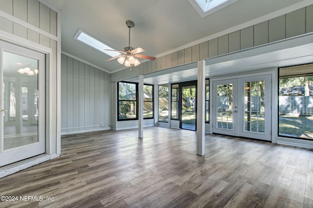 unfurnished sunroom featuring vaulted ceiling with skylight, a ceiling fan, and french doors