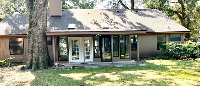 back of house featuring french doors, roof with shingles, a lawn, and a chimney