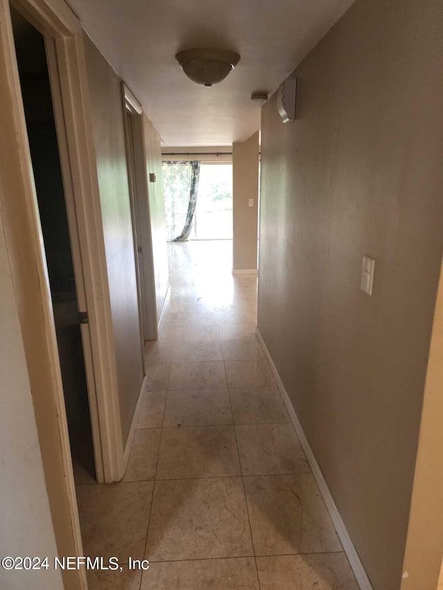 hallway featuring light tile patterned floors and baseboards