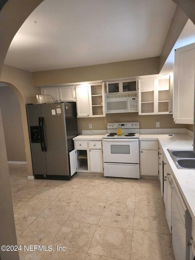 kitchen featuring arched walkways, white appliances, a sink, light countertops, and open shelves