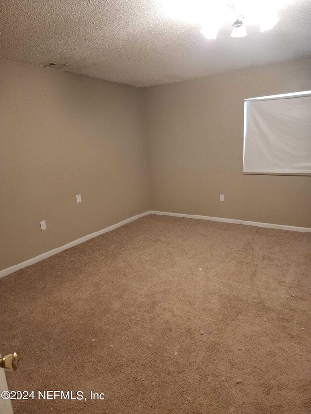 carpeted empty room featuring a textured ceiling and baseboards