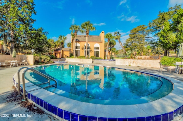 community pool with fence and a patio