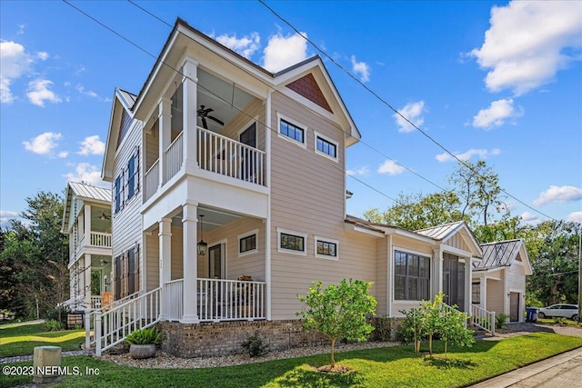 view of side of home with a balcony, a yard, and ceiling fan