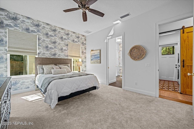 bedroom with a textured ceiling, a barn door, ceiling fan, and carpet flooring