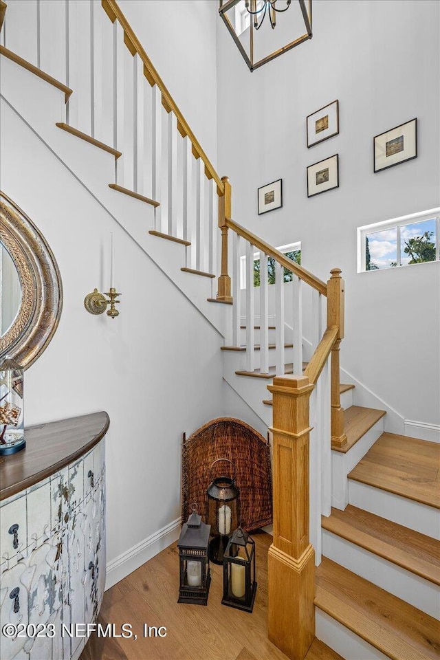 stairway with hardwood / wood-style floors, a towering ceiling, and a wealth of natural light