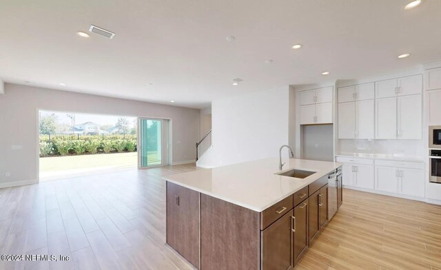 kitchen with a sink, visible vents, white cabinetry, open floor plan, and appliances with stainless steel finishes