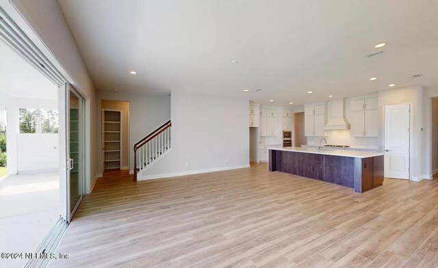 kitchen with light wood finished floors, custom exhaust hood, light countertops, and recessed lighting