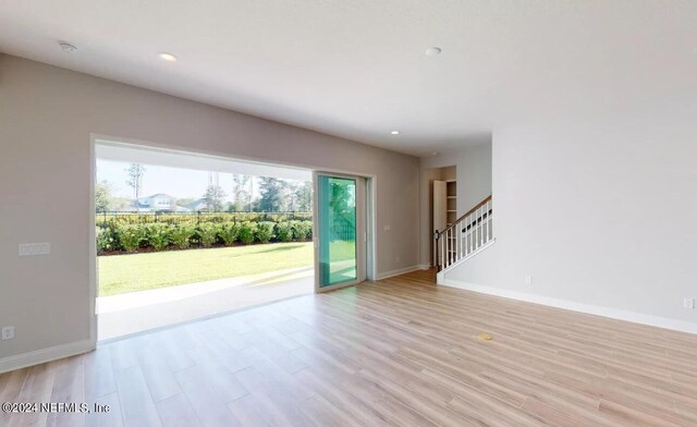 unfurnished living room featuring recessed lighting, light wood-style flooring, baseboards, and stairs