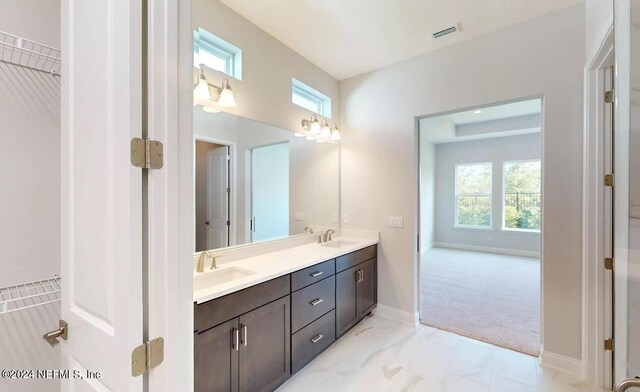 full bath featuring plenty of natural light, marble finish floor, a sink, and double vanity