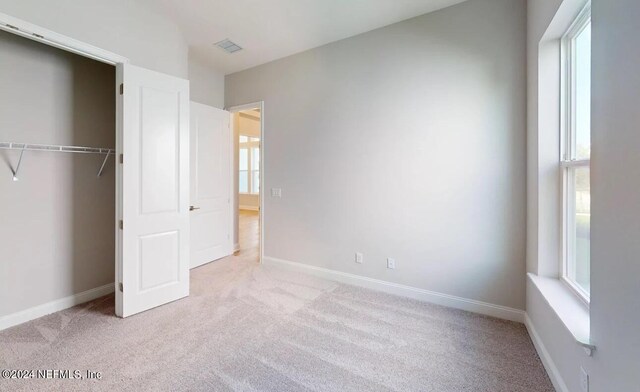 unfurnished bedroom featuring a closet, carpet flooring, visible vents, and baseboards