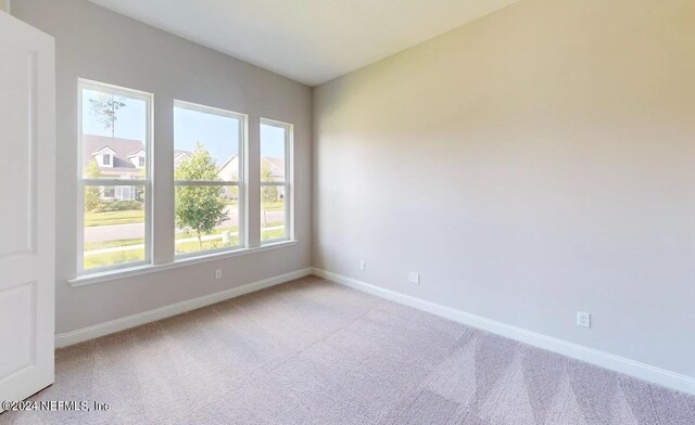 empty room featuring baseboards and light colored carpet