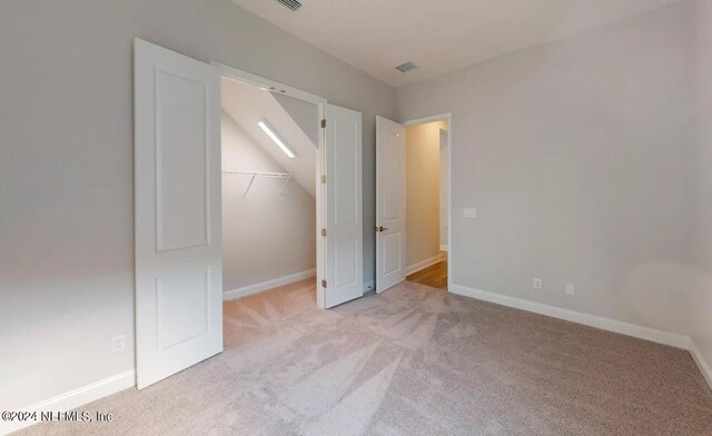 unfurnished bedroom with baseboards, visible vents, carpet, a spacious closet, and a closet