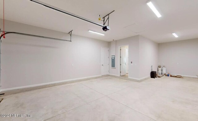 garage featuring electric panel, baseboards, and a garage door opener