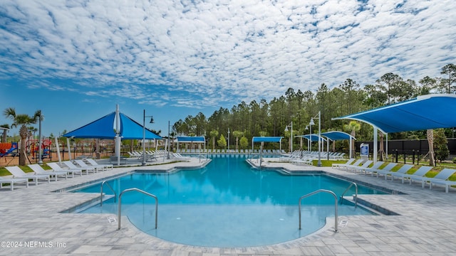 view of swimming pool with a playground and a patio area