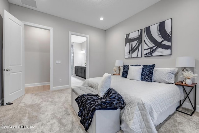 bedroom featuring light carpet and connected bathroom