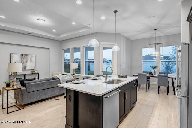 kitchen featuring pendant lighting, sink, light hardwood / wood-style flooring, stainless steel appliances, and an island with sink