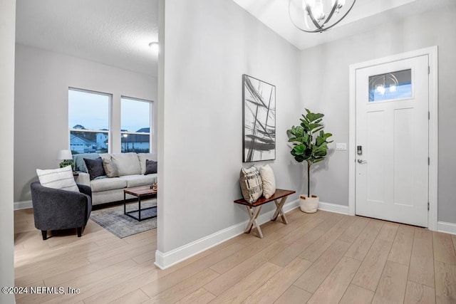 foyer featuring an inviting chandelier, a textured ceiling, and light wood-type flooring