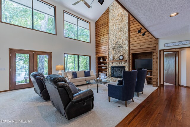 living room featuring ceiling fan, built in features, a fireplace, high vaulted ceiling, and a textured ceiling