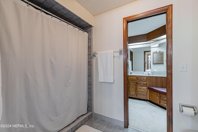 bathroom featuring a textured ceiling, tile patterned floors, vanity, and walk in shower