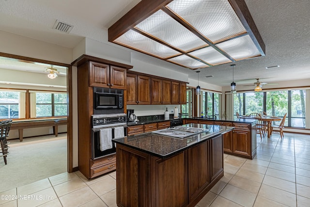 kitchen featuring kitchen peninsula, light colored carpet, dark stone counters, black appliances, and a center island