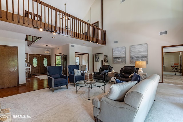 living room featuring light carpet, a towering ceiling, and a notable chandelier