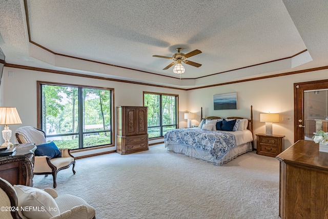 carpeted bedroom with ceiling fan, a tray ceiling, a textured ceiling, and ornamental molding