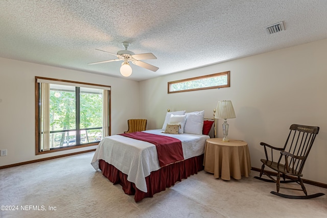 bedroom featuring ceiling fan, light colored carpet, and a textured ceiling