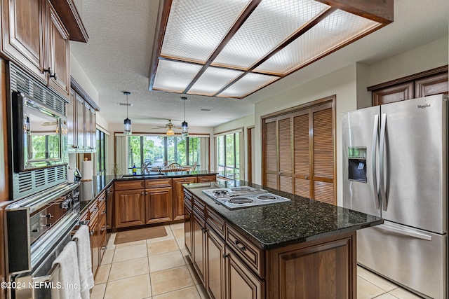 kitchen with ceiling fan, appliances with stainless steel finishes, light tile patterned flooring, and a kitchen island