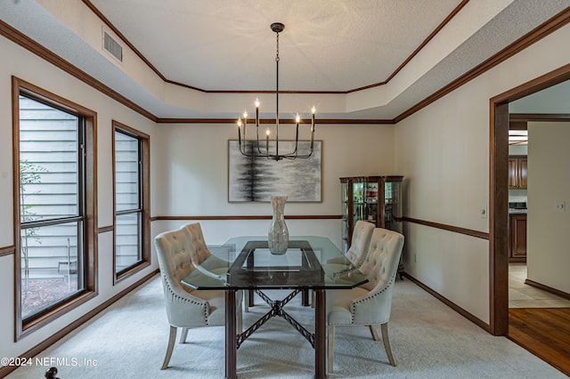 carpeted dining room featuring an inviting chandelier, a wealth of natural light, ornamental molding, and a tray ceiling