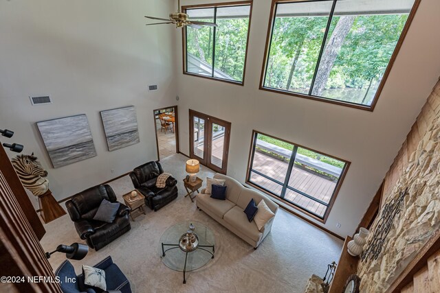 carpeted living room with ceiling fan and a towering ceiling