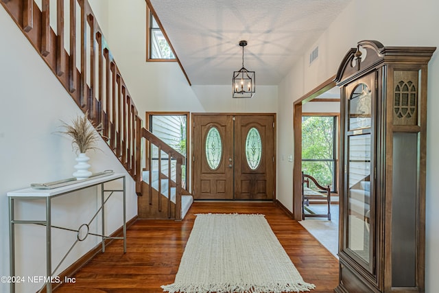 foyer with a textured ceiling, dark hardwood / wood-style flooring, and a notable chandelier