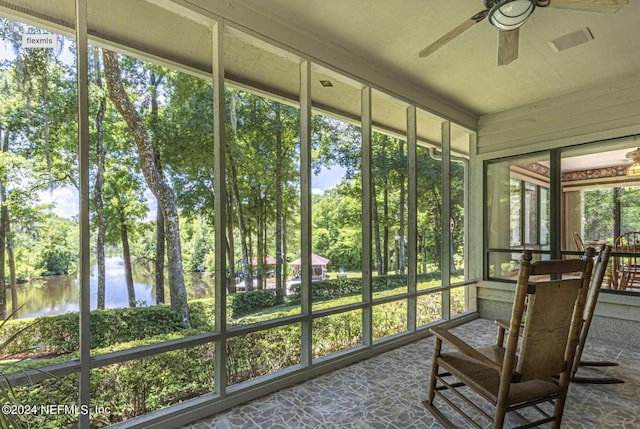 sunroom / solarium featuring ceiling fan and a water view