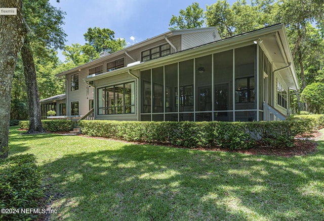 rear view of property with a sunroom and a yard