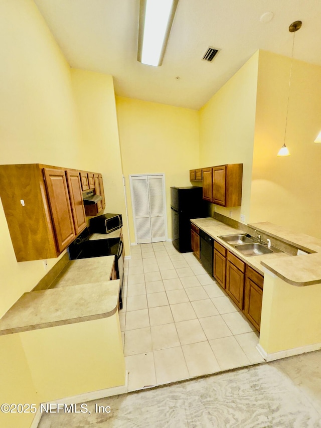 kitchen featuring hanging light fixtures, light tile patterned floors, black appliances, and sink